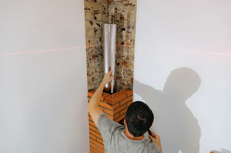 Technician measuring chimney interior with laser level for chimney liner replacement