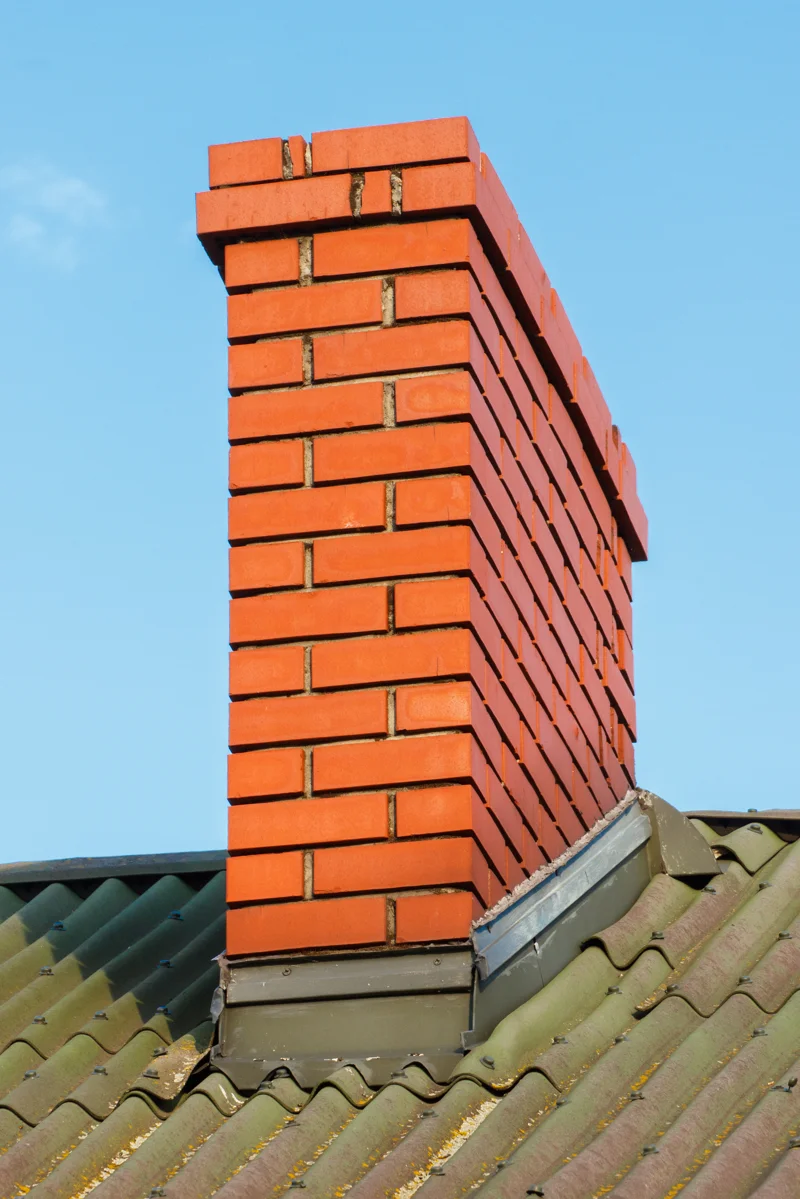 Brick chimney rebuilt showing chimney rebuilding on green corrugated metal roof