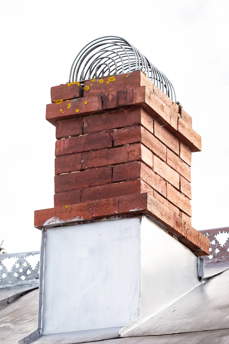 Brick chimney with stainless steel coil animal screen installation on rooftop